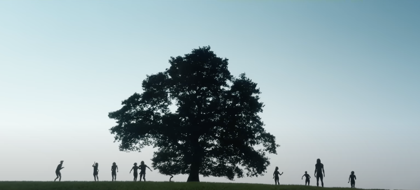film still from 28 Years Later showing silhouettes of people around a large tree