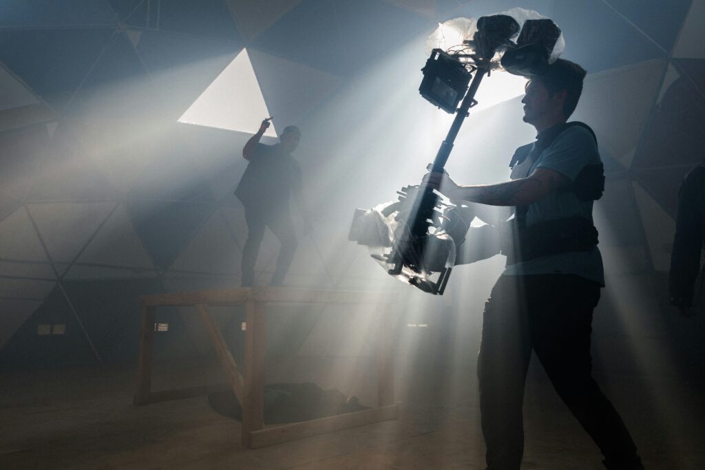 image of a man filming in a dark room with rays of light coming from above