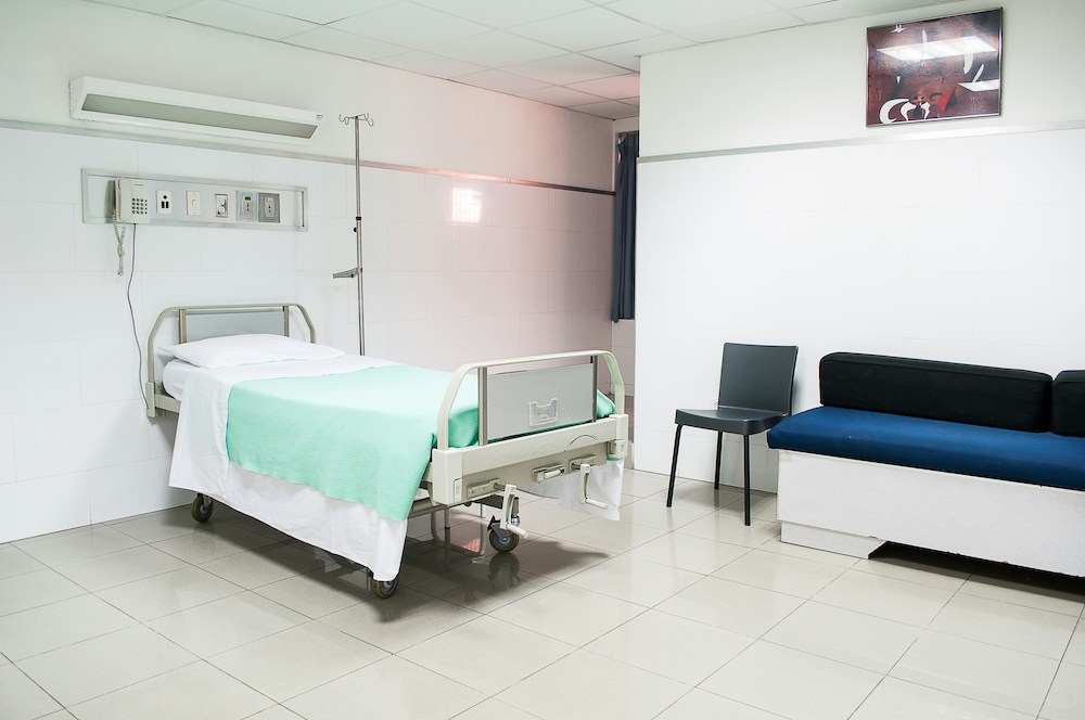 image of a simple hospital room with a hospital bed and chair 