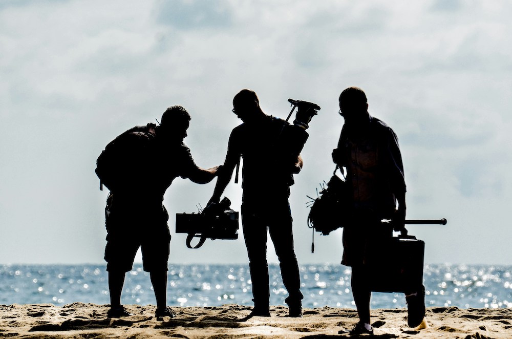 image of three men filming on a beach