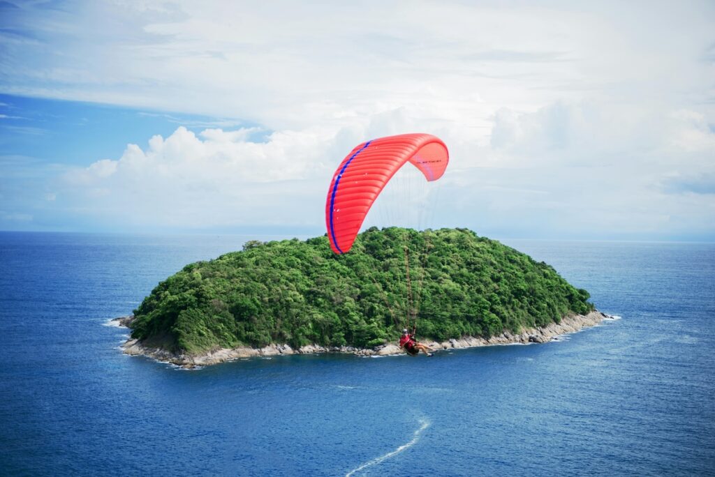 image of a paraglider approaching a lush island in the middle of the ocean