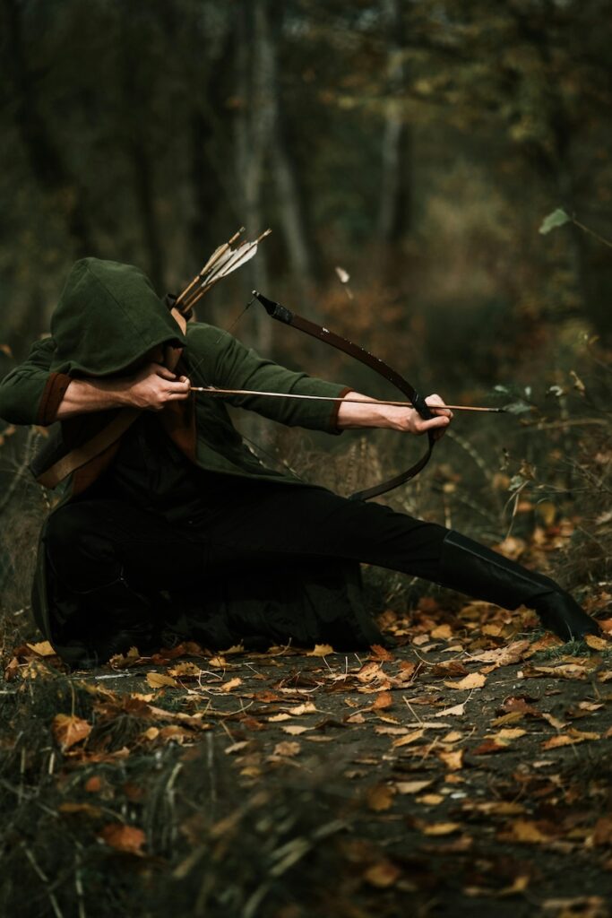 image of an archer aiming his box and arrow in a woodland