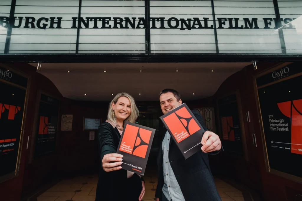 image of two people holding up brochures for the Edinburgh International Film festival