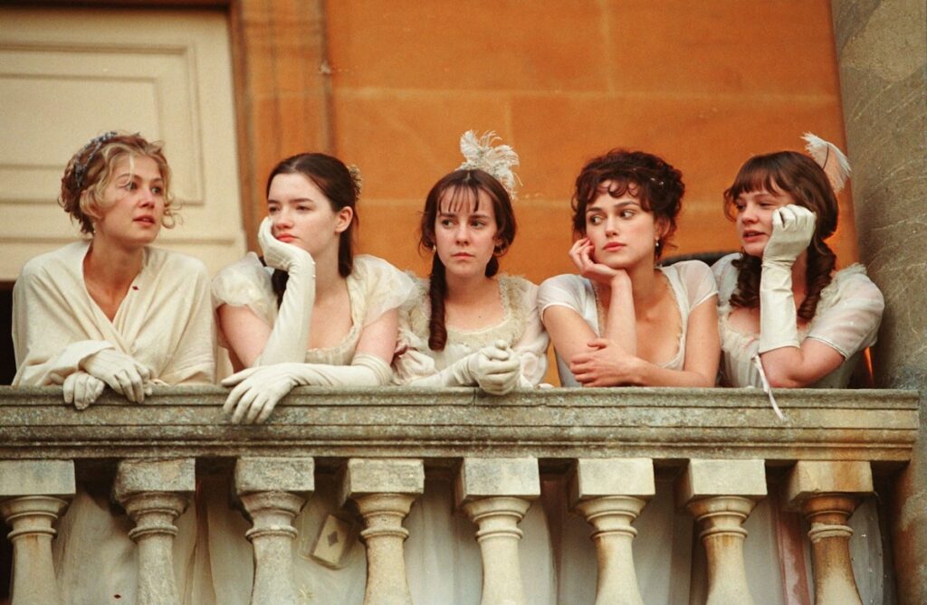 Film still of the Bennet daughters in a row leaning on the balcony at Netherfield (Basildon Park)