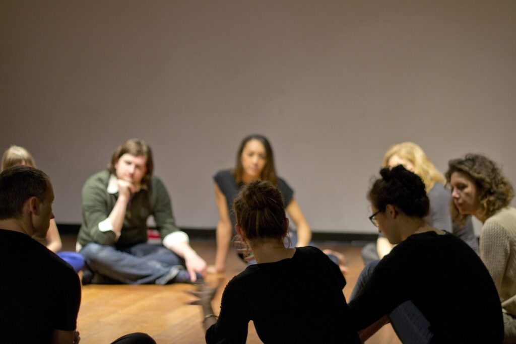 A group of students sitting in a circle onstage at Tisch School of the Arts