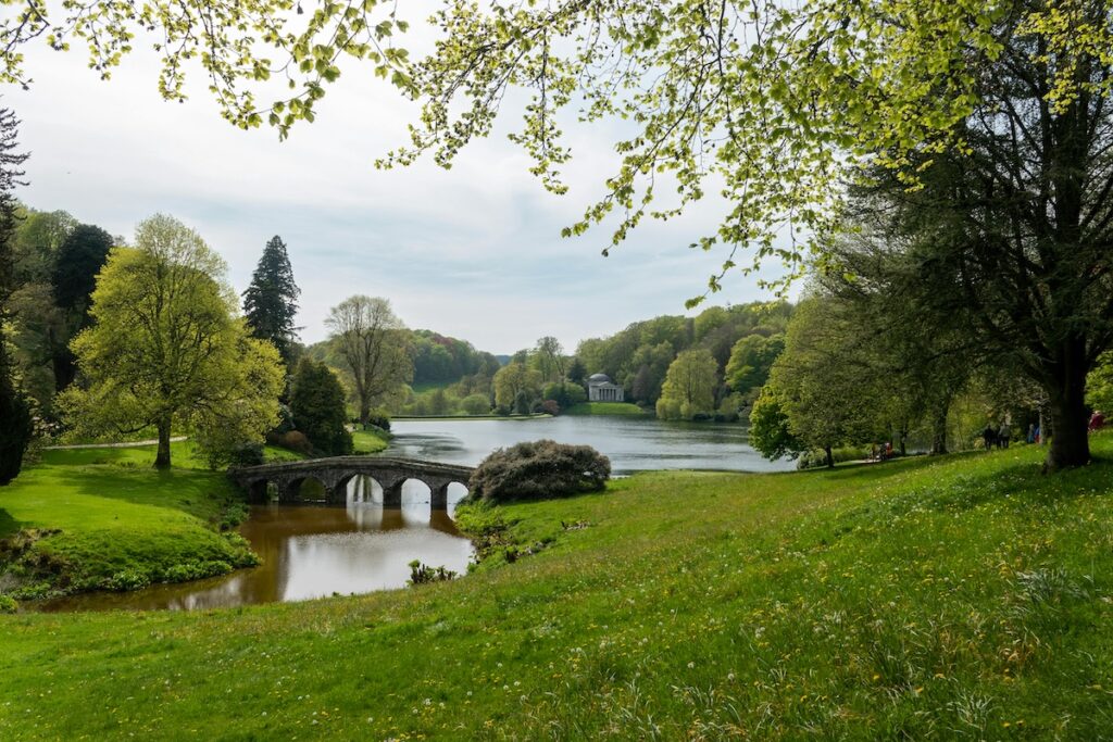 Summer views of the lake, bridge and Temple of Apollo in the distance at Stourhead