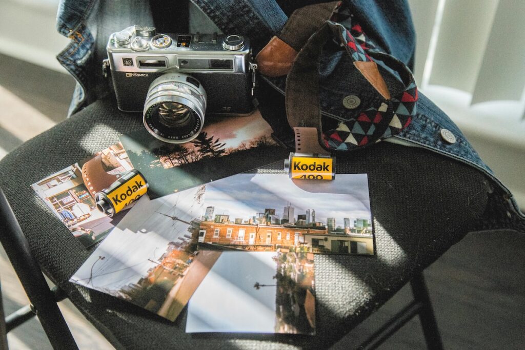 Rolls of Kodak film, printed photos and a classic film camera laid out on a chair