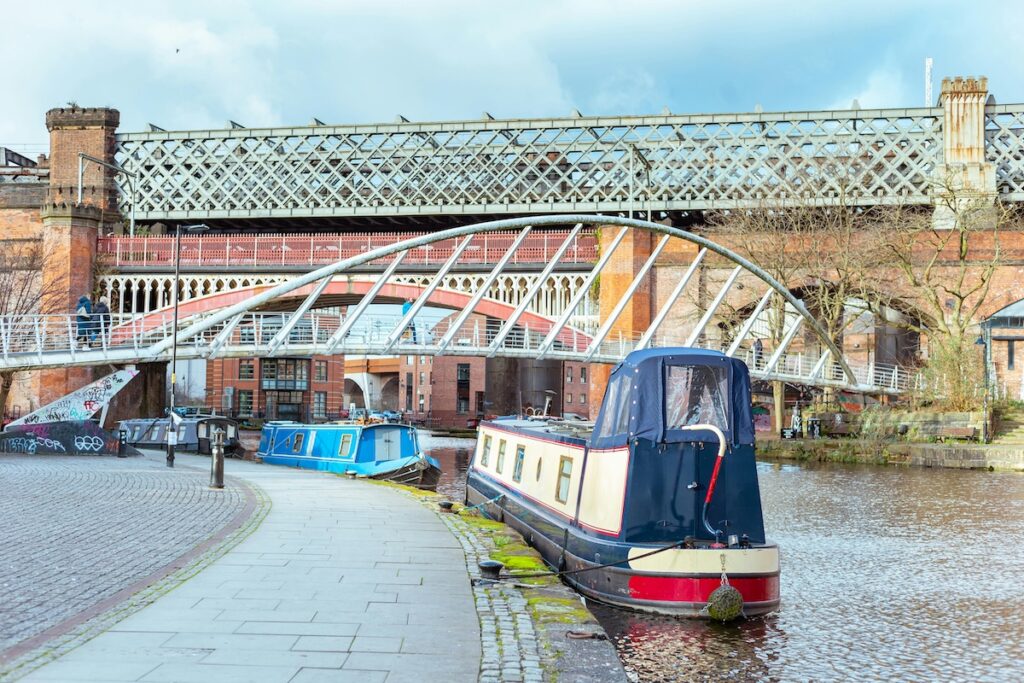 Manchester filming location - canal side path with moored house boats in Castlefield