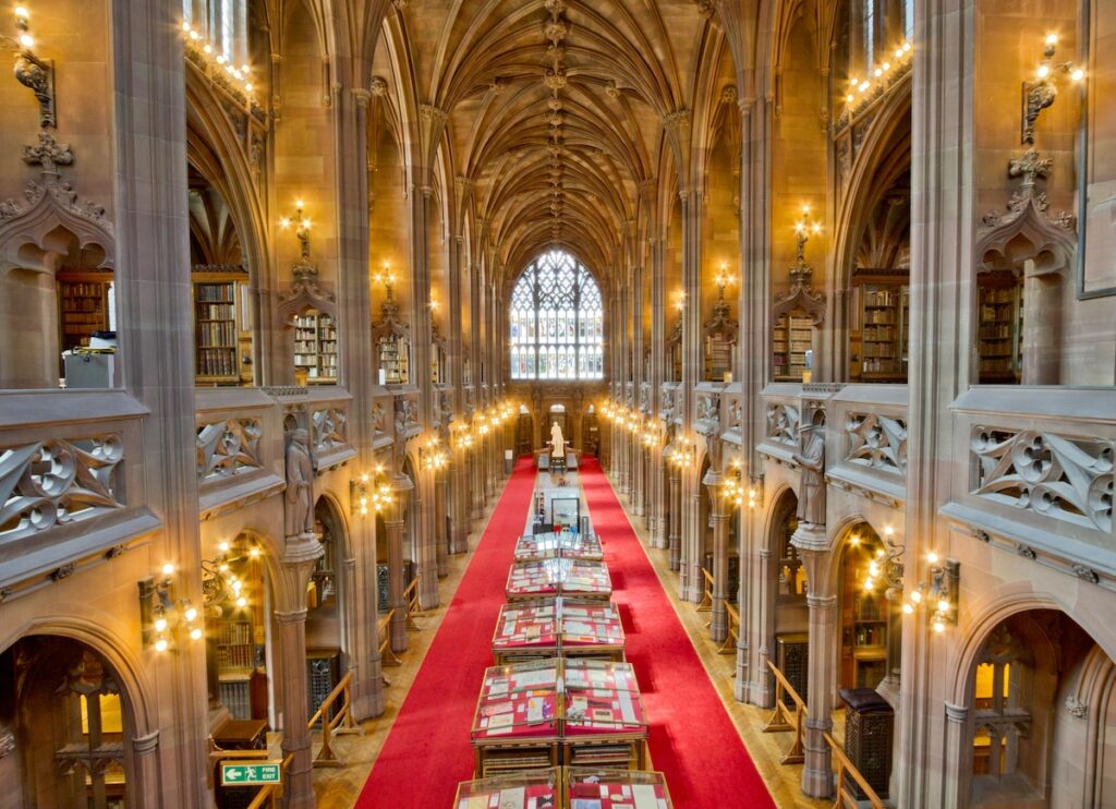 Long corridor with vaulted ceiling and  stained glass window of John Rylands Library