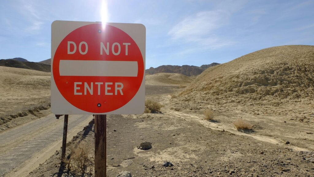 orange and white 'Do Not Enter' sign next to a road in the desert