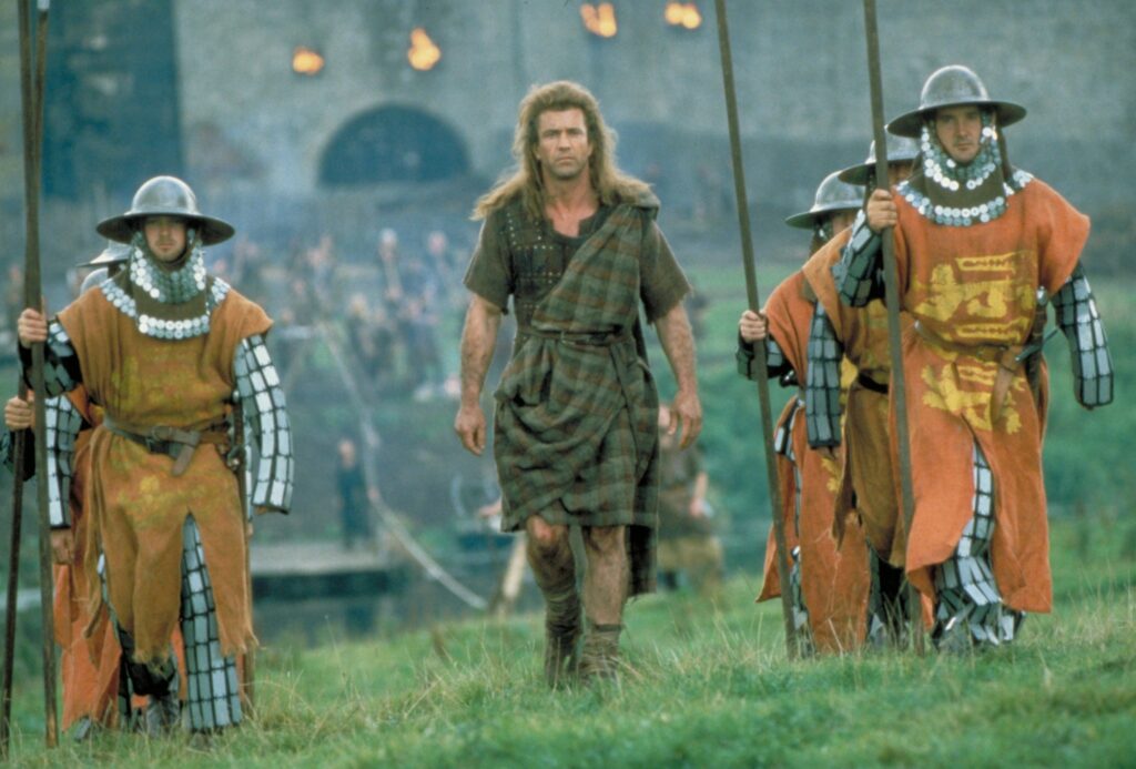 Film still from Braveheart (1995) showing characters marching across a field
