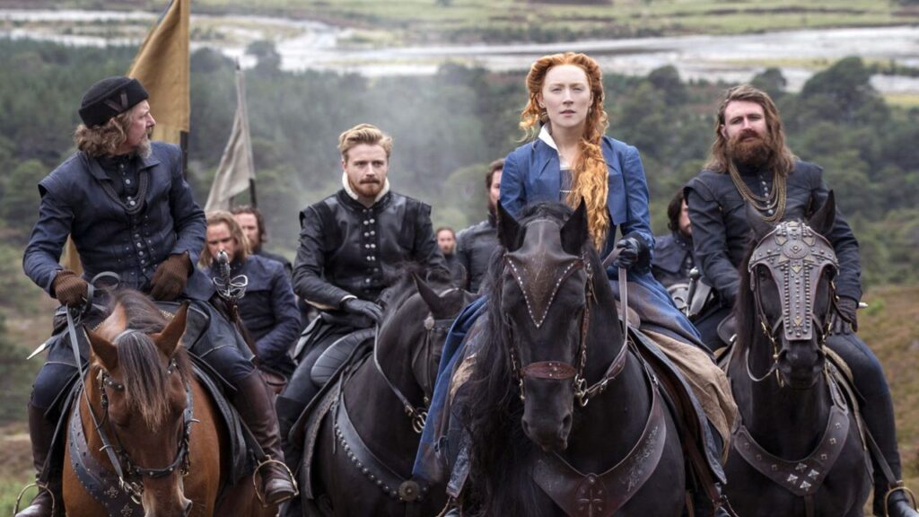 Film still from Mary Queen of Scots (2018) showing characters on horseback in the countryside