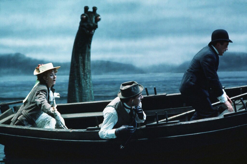 Film still from The Private Life of Sherlock Holmes (1970) showing characters in a small boat on the loch with the loch ness monster in the background